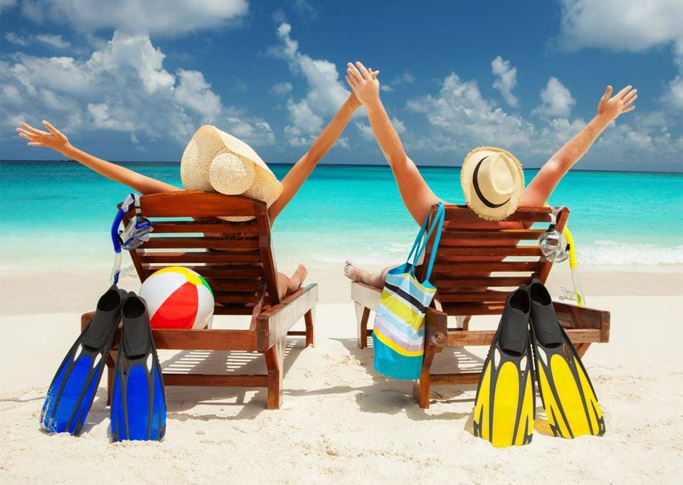 Two people sitting on beach chairs with arms raised.