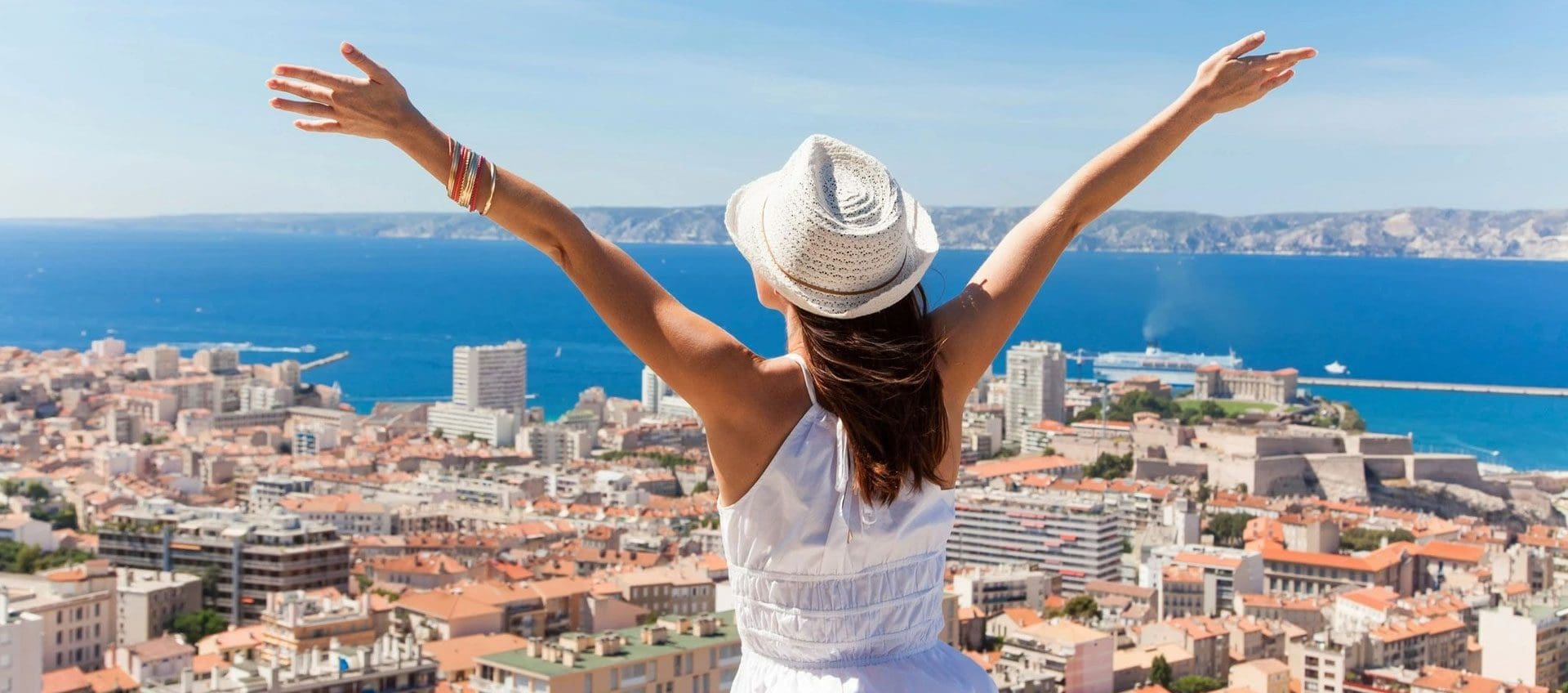 A woman in white shirt and hat raising her arms.