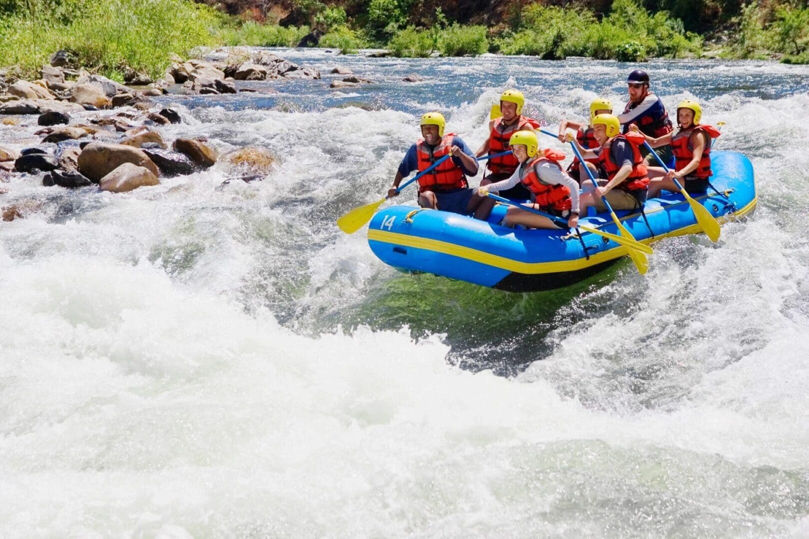 A group of people in yellow helmets are on a raft.